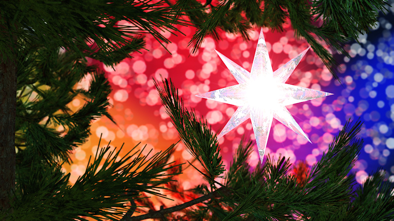 A bright star hanging in a Christmas tree against a sparkling bokeh background in all the colors of the rainbow.