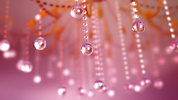 A 3D macro shot of a crystal chandelier. Myriads of strands of sparkling glass beads catch the light to create a lovely bokeh in the background. The b...